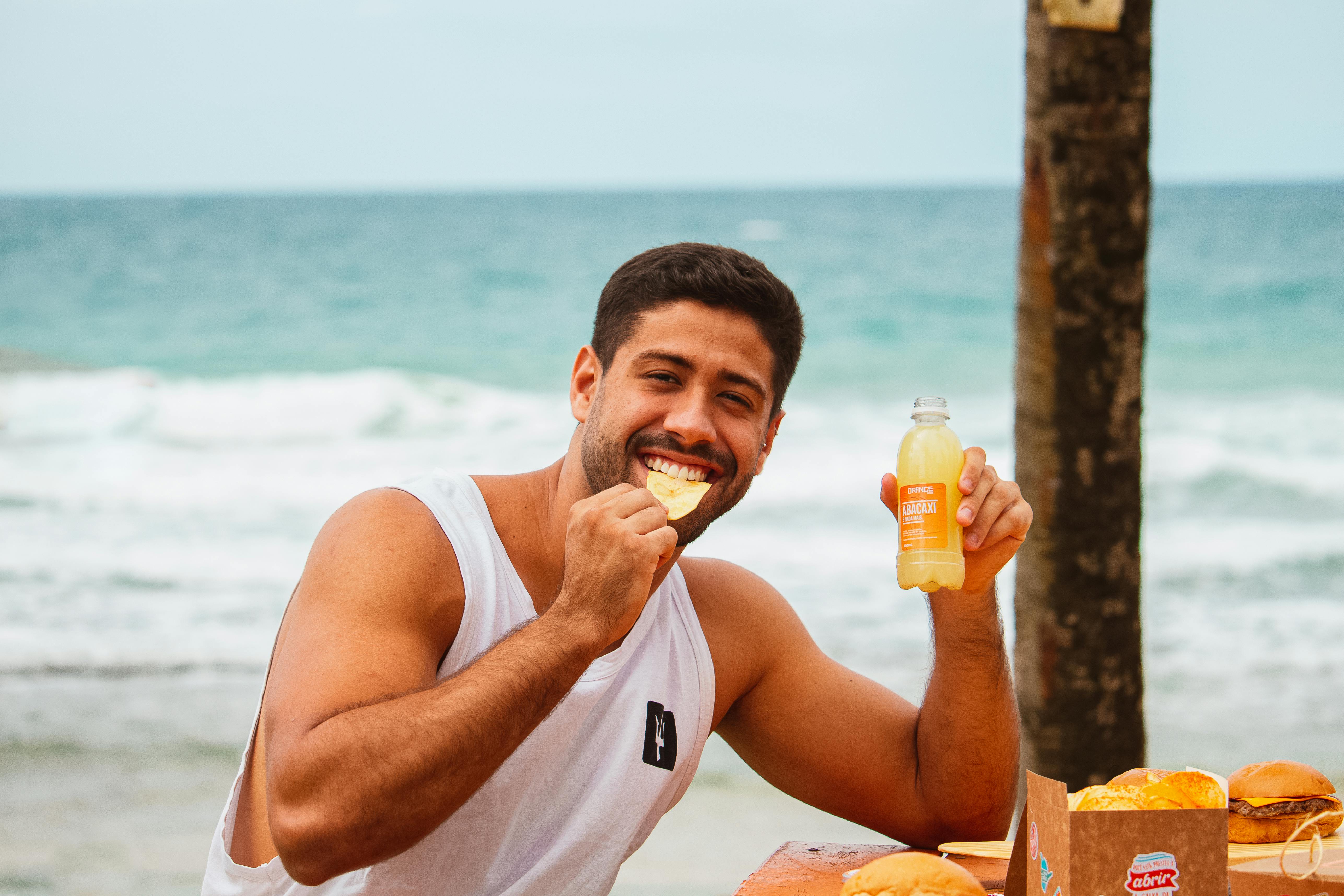 Man eating STEAK FUEL air-cured biltong outdoors near the beach.